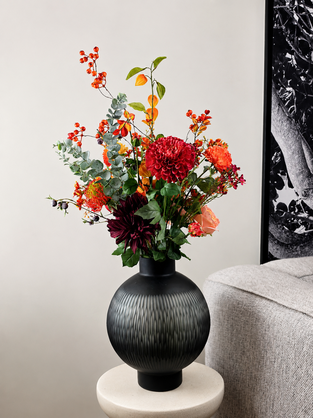 Kraftvoller Seidenblumenstrauß Julia mit roten und orangefarbenen Kunstblumen in dunkler Vase